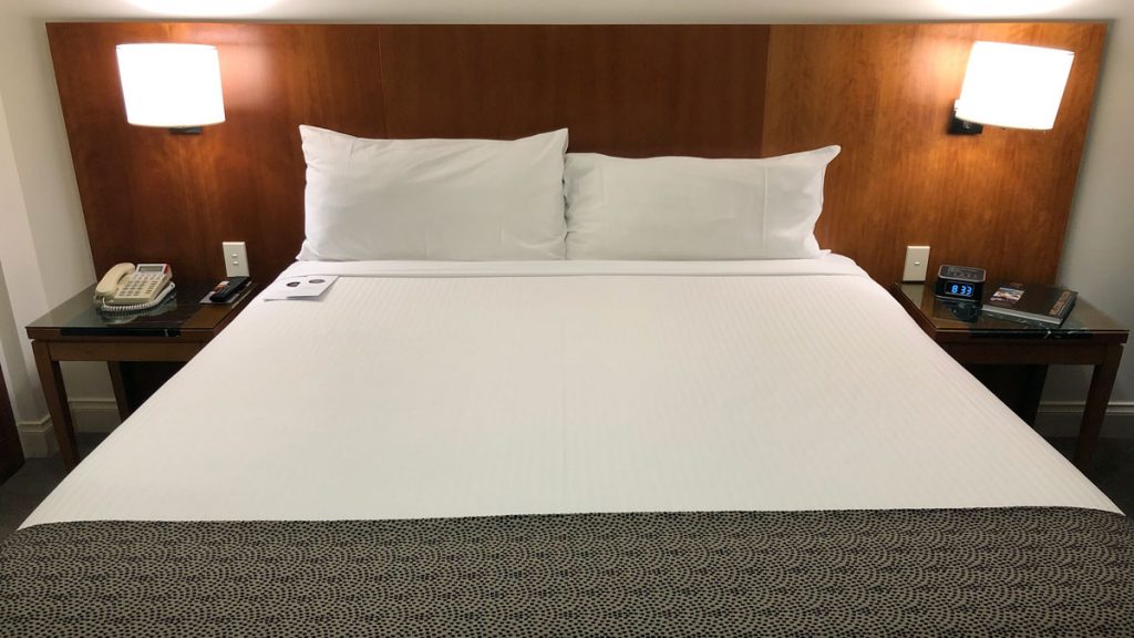 a bed with white sheets and pillows