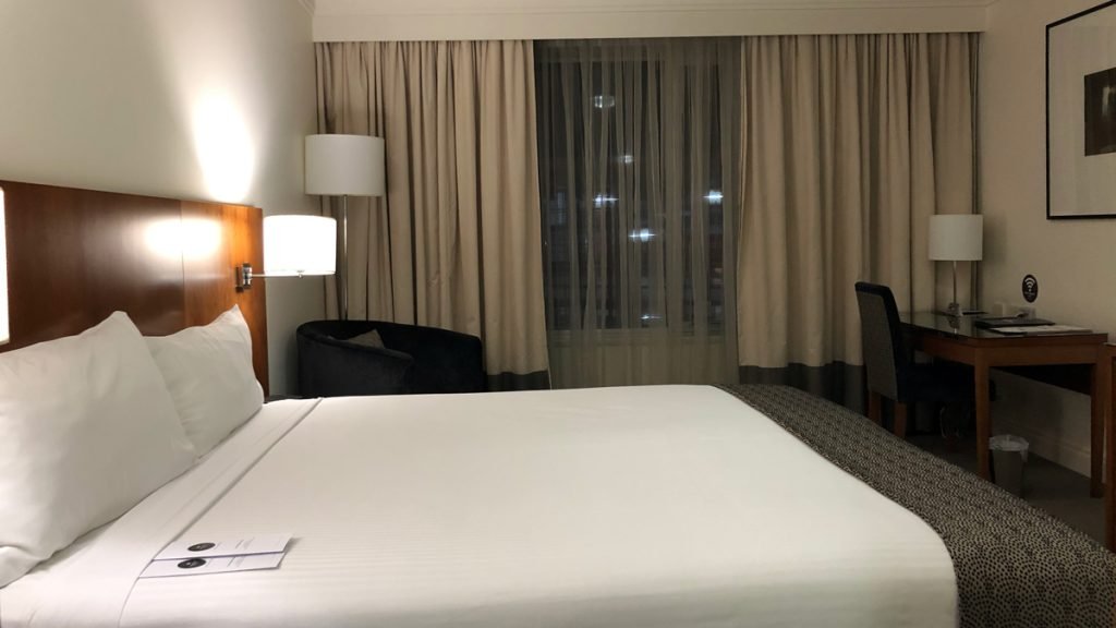 a bed with a lamp and a chair in a hotel room