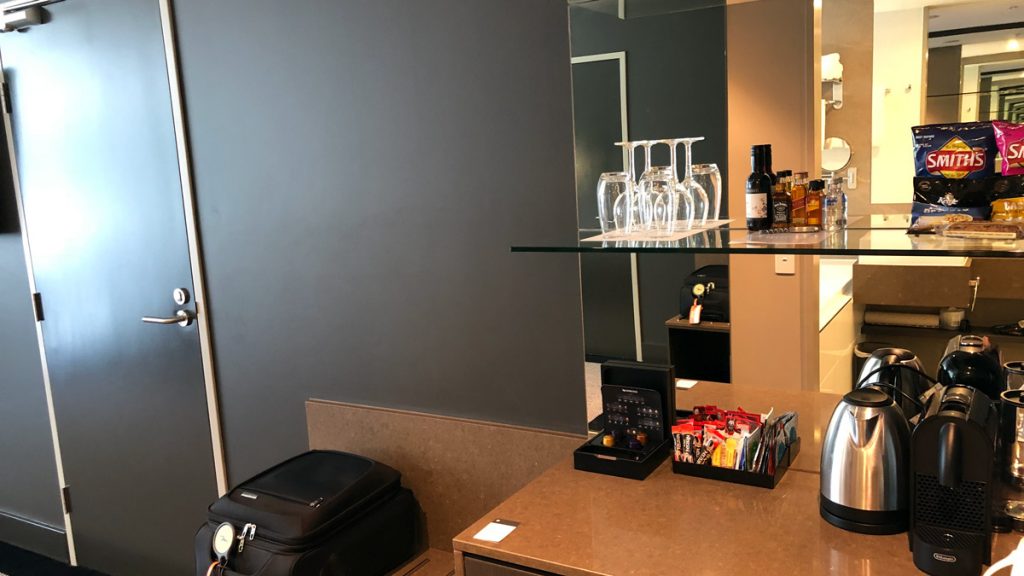 a glass shelf with wine glasses and a suitcase