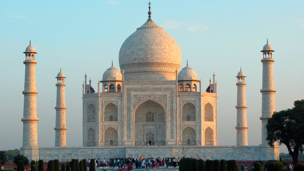 a large white building with a dome and towers with Taj Mahal in the background