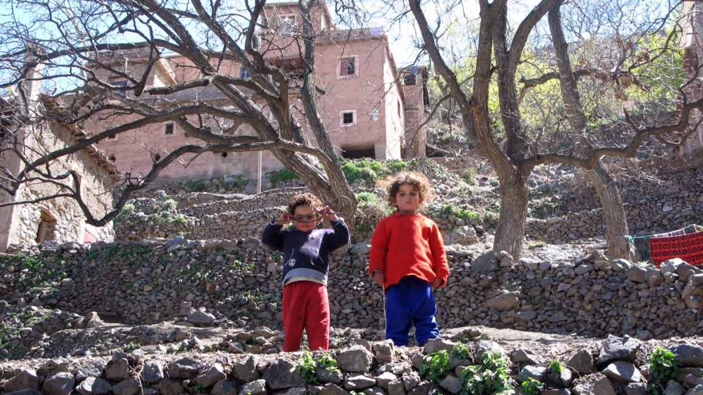 a couple of children standing on rocks