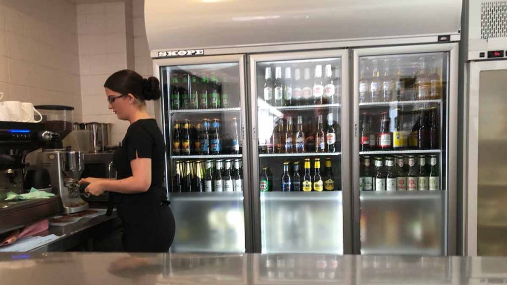 a woman standing behind a counter with a beverage display