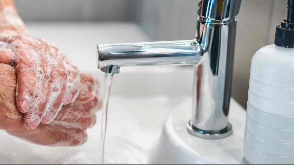 a person washing their hands under a faucet