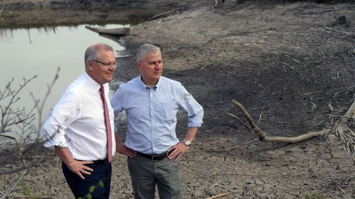 a couple of men standing next to a lake