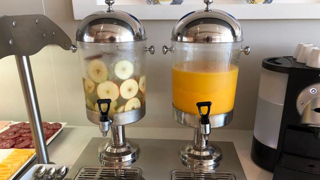 a beverage dispenser with apples and orange juice