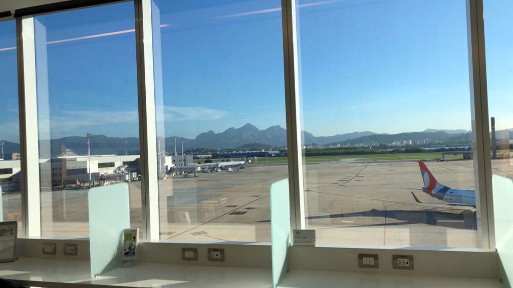 a window with a view of a runway and mountains in the background