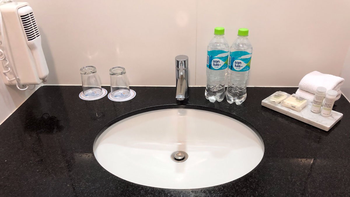 a sink with bottles of water and glasses on it