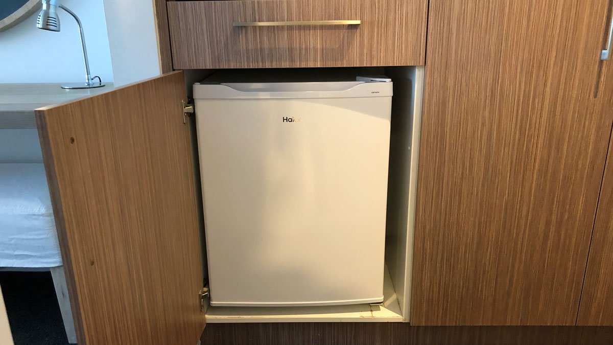 a small white refrigerator in a cabinet