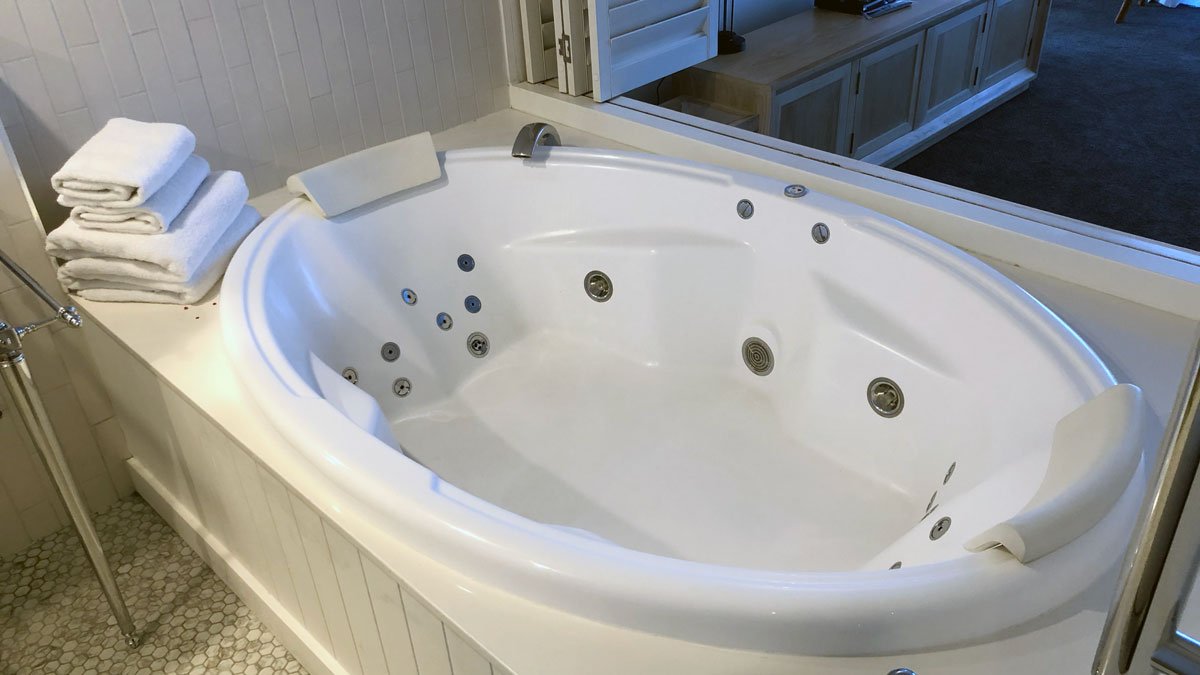 a white round bathtub with silver knobs