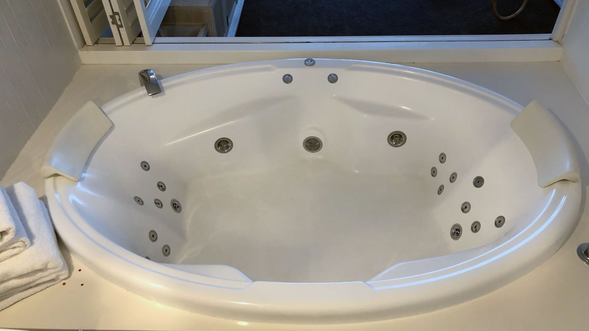 a white round bathtub with silver buttons