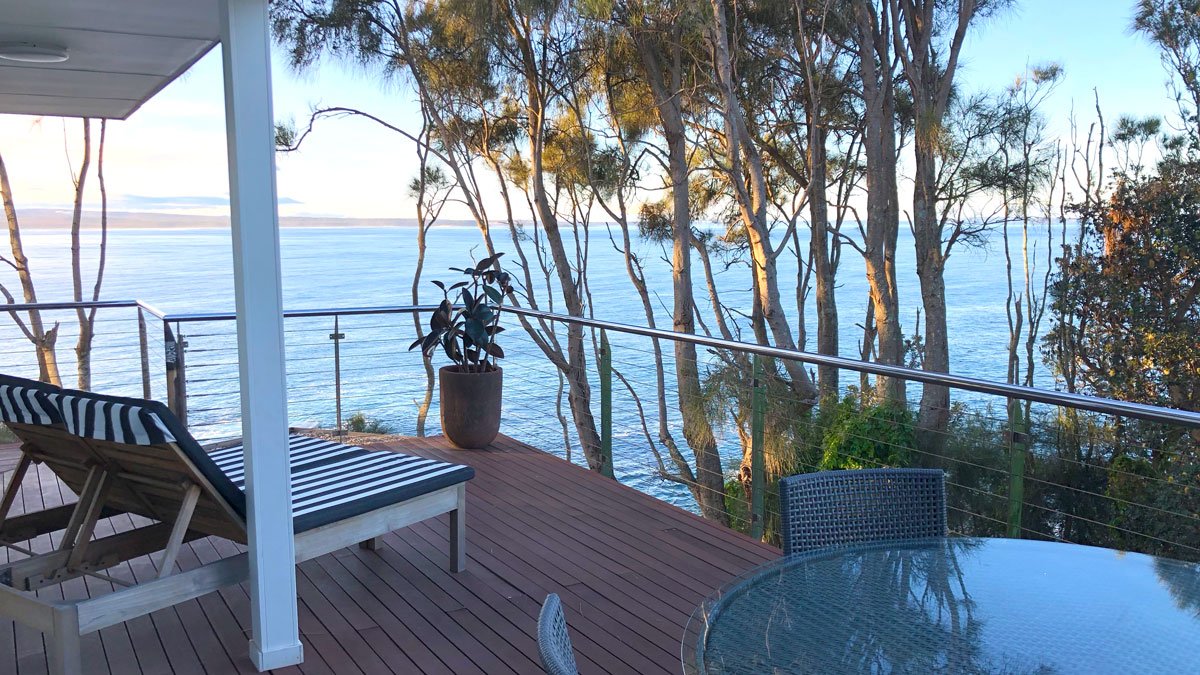 a deck with a table and chairs overlooking the water