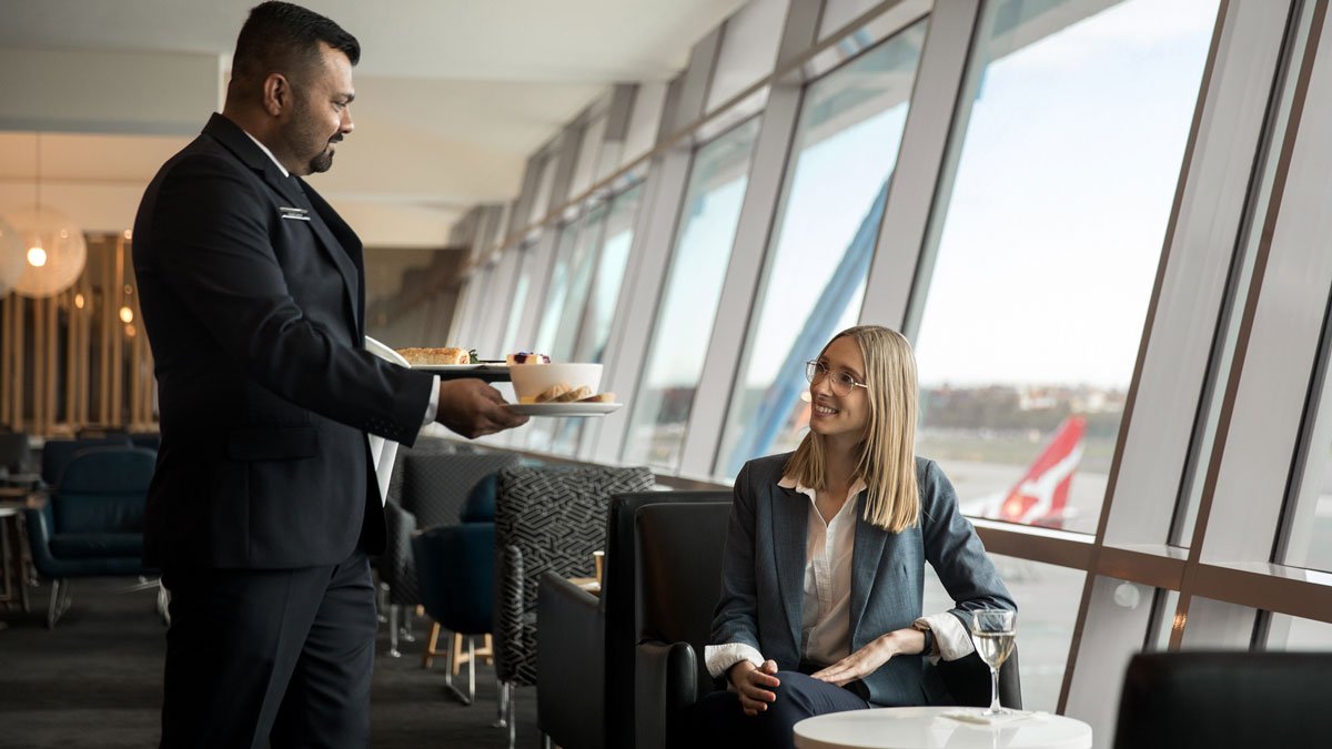 a man holding a tray of food and a woman sitting at a table