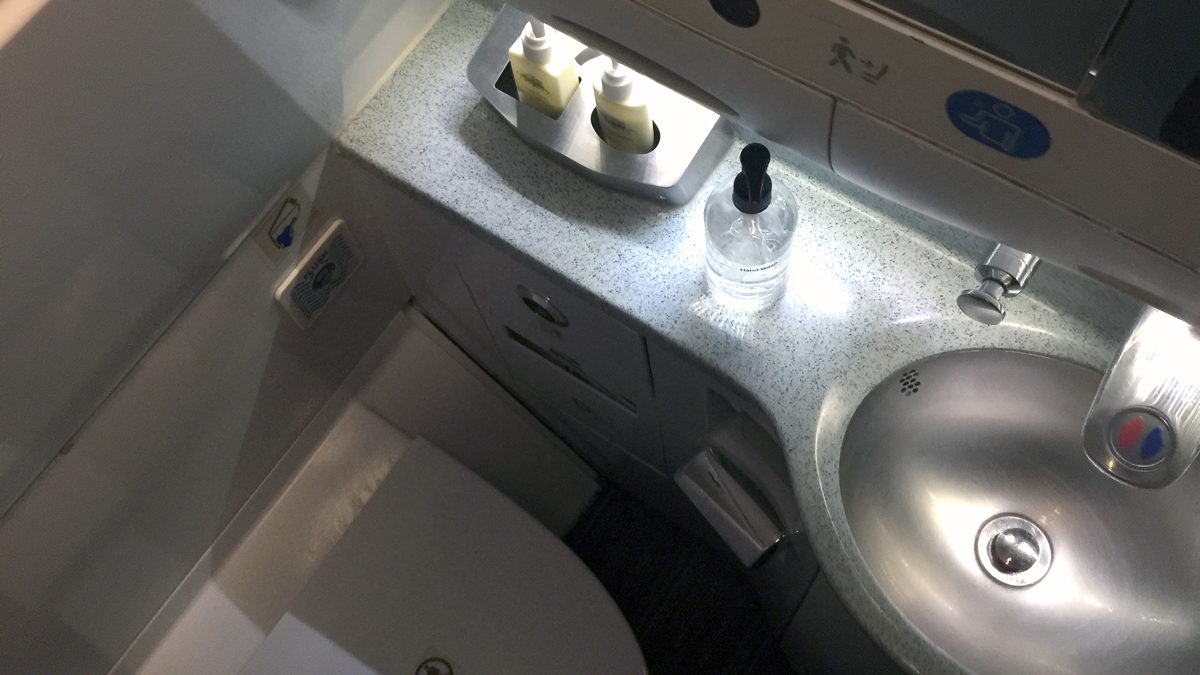 a toilet and sink with soap bottles on the counter