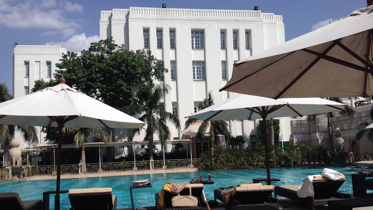 a pool with umbrellas and chairs in front of a building