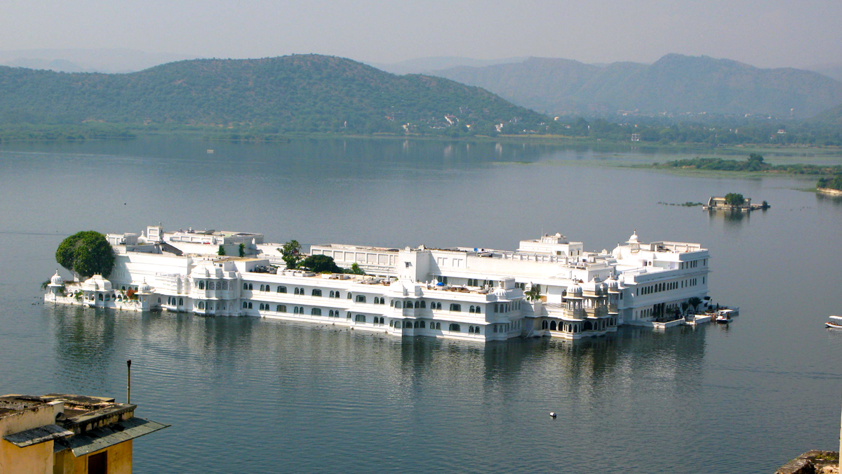 a large white building in water with Lake Palace in the background