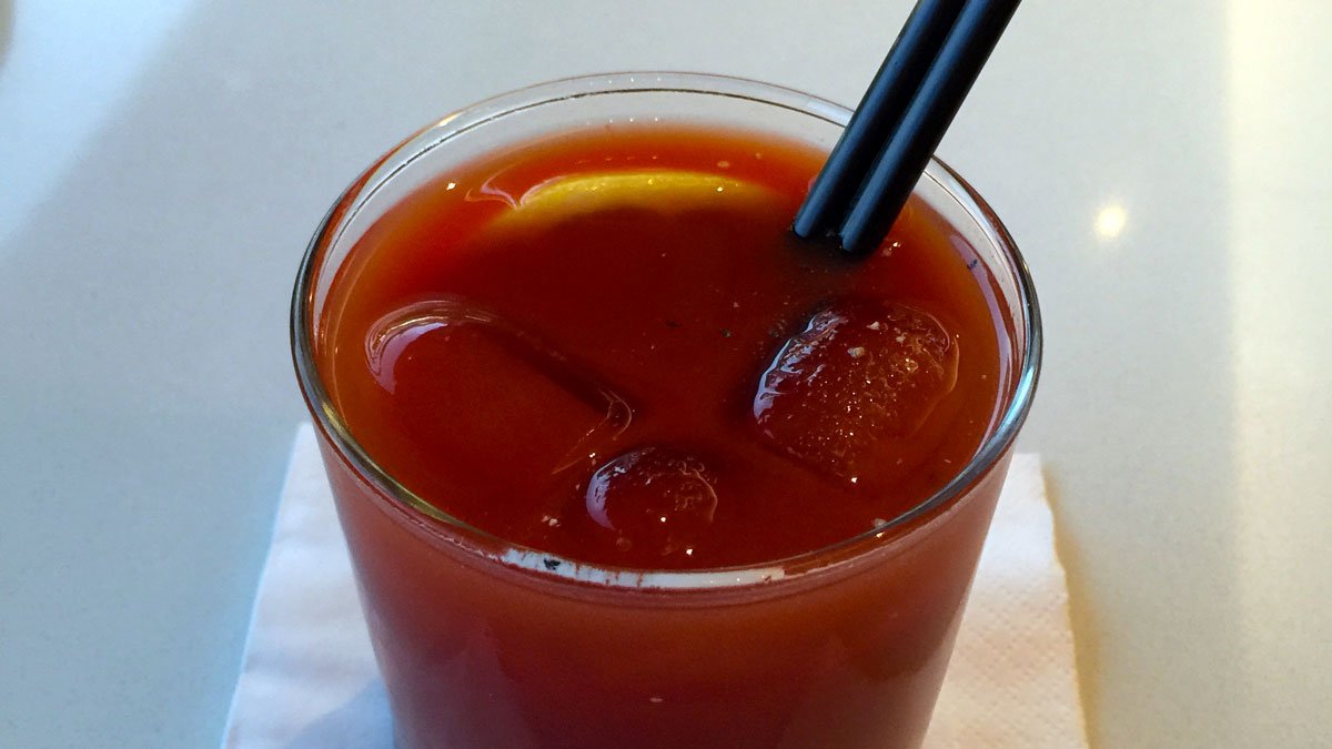 a glass of liquid with ice and a straw