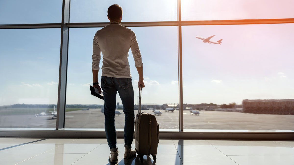 a man standing in front of a window with a suitcase