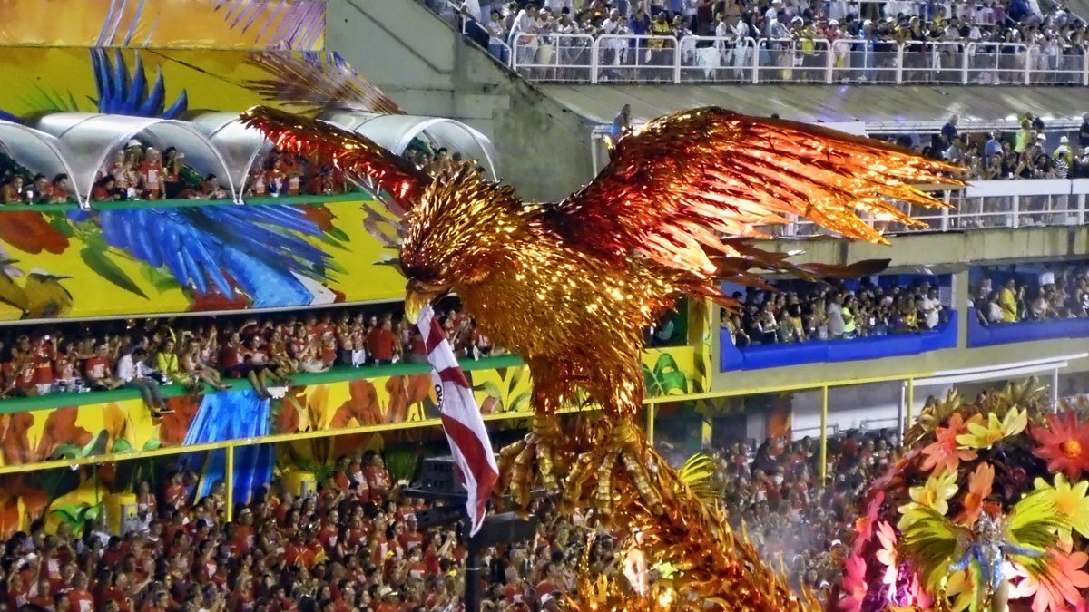 a large bird with wings and a flag in front of a crowd