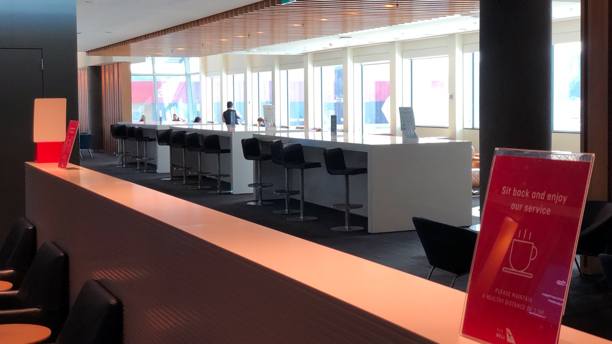 a long white counter with black chairs and a red sign