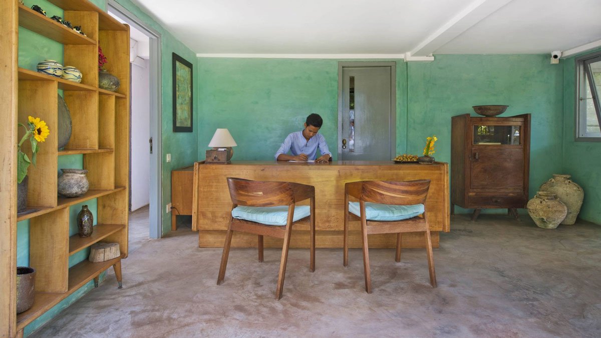 a man sitting at a desk in a room with chairs