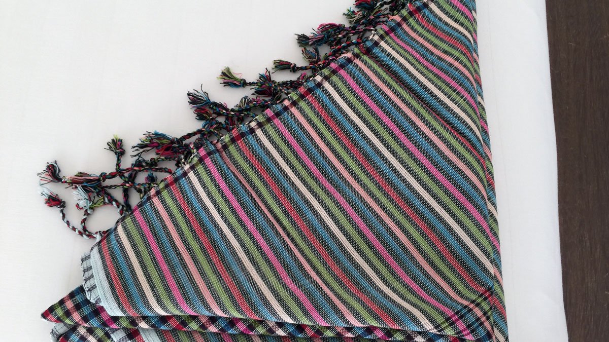 a colorful striped blanket with tassels