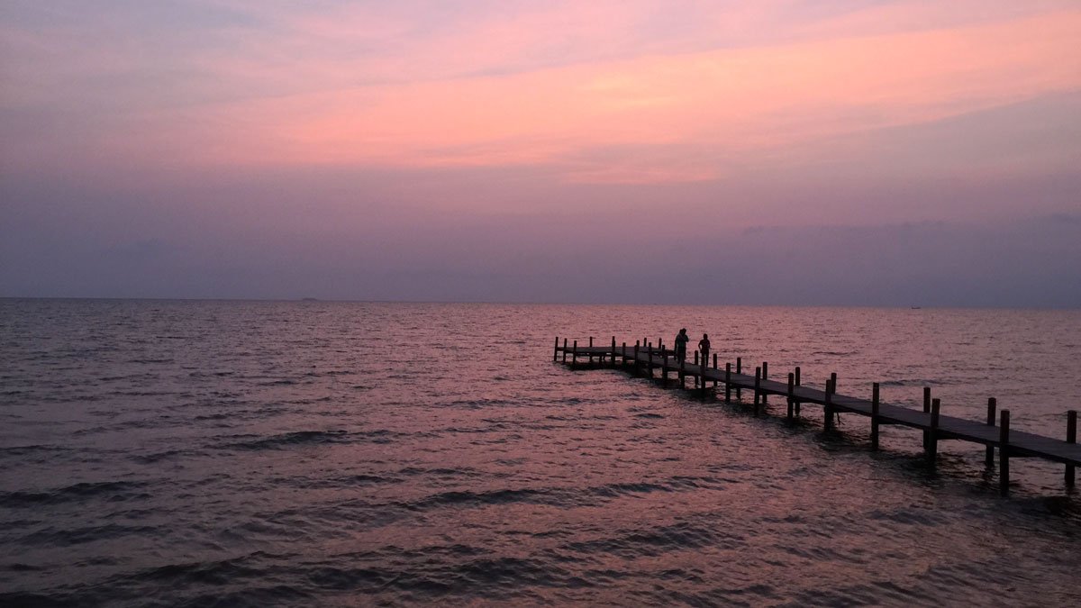 a group of people standing on a dock in the water