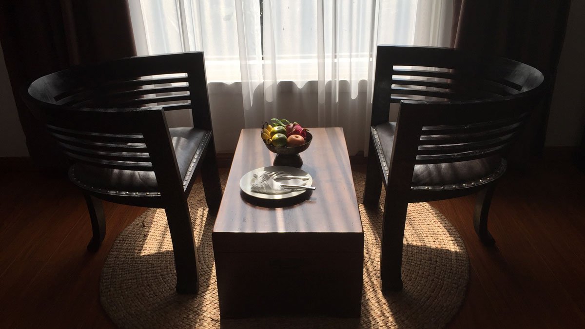 a table with fruit on it and two chairs in front of a window