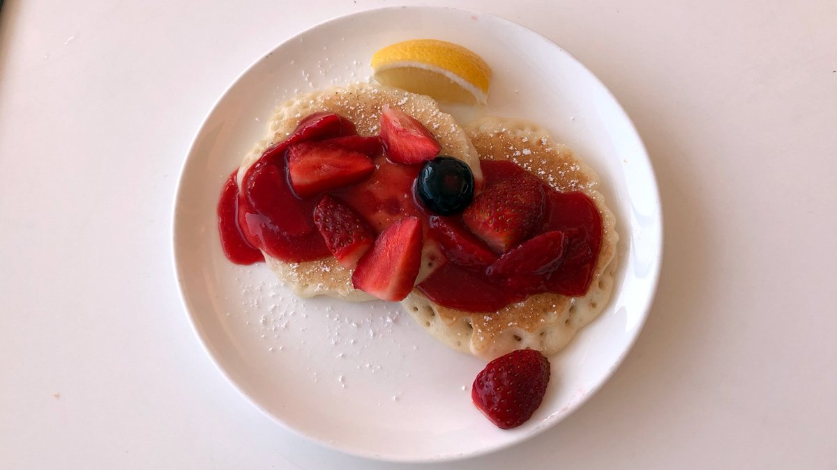 a plate of pancakes with fruit and syrup