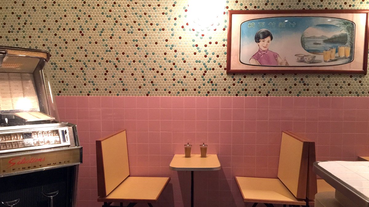 a pink and white tiled wall with a table and chairs