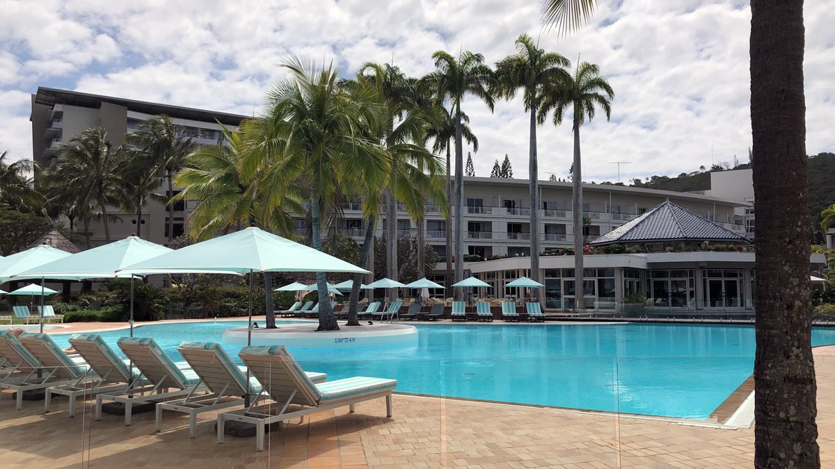 a pool with lounge chairs and umbrellas in front of a building