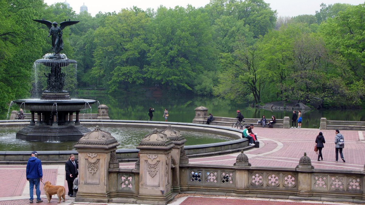 a group of people sitting on a stone walkway next to a pond