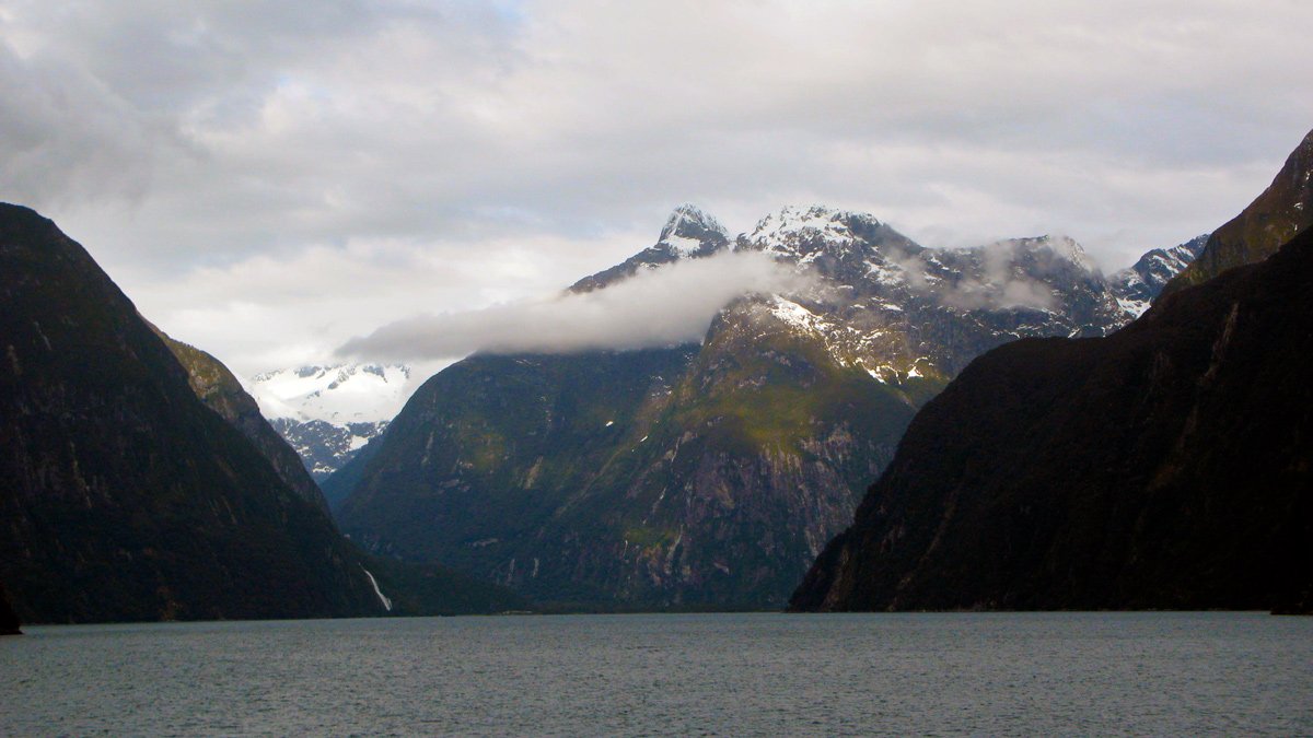 a body of water with mountains and clouds