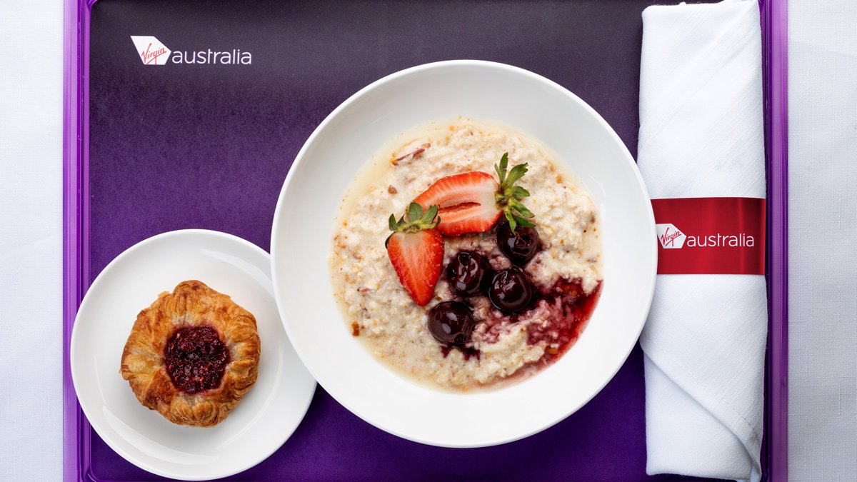 a bowl of oatmeal with fruit and a pastry on a plate