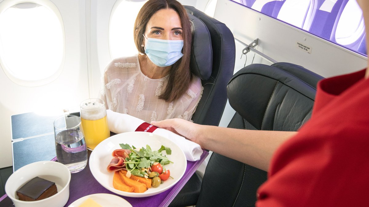 a woman in a mask sitting in a chair with a plate of food