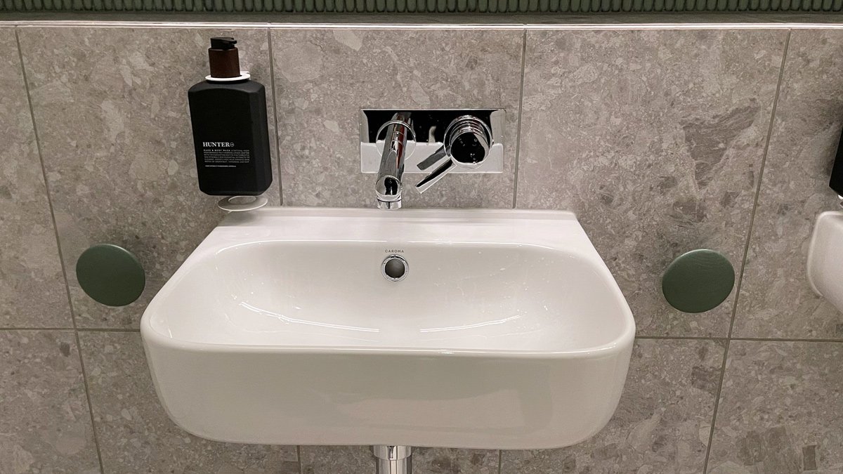 a white sink with silver faucet and black soap dispenser