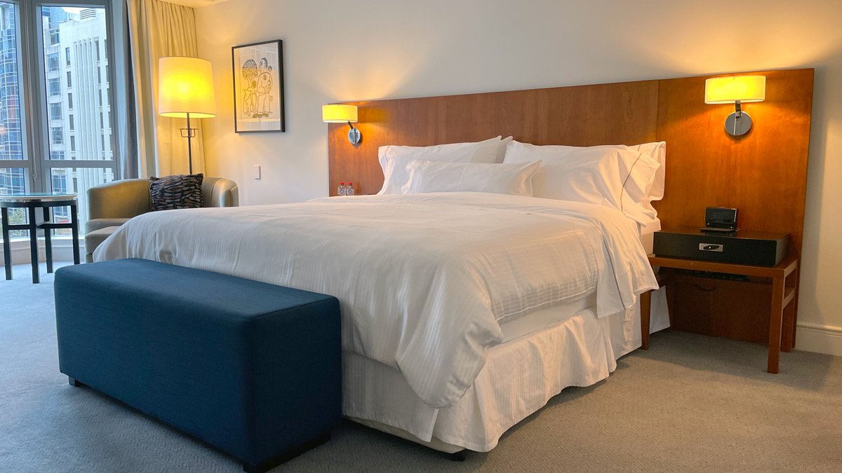 a bed with white sheets and a blue ottoman