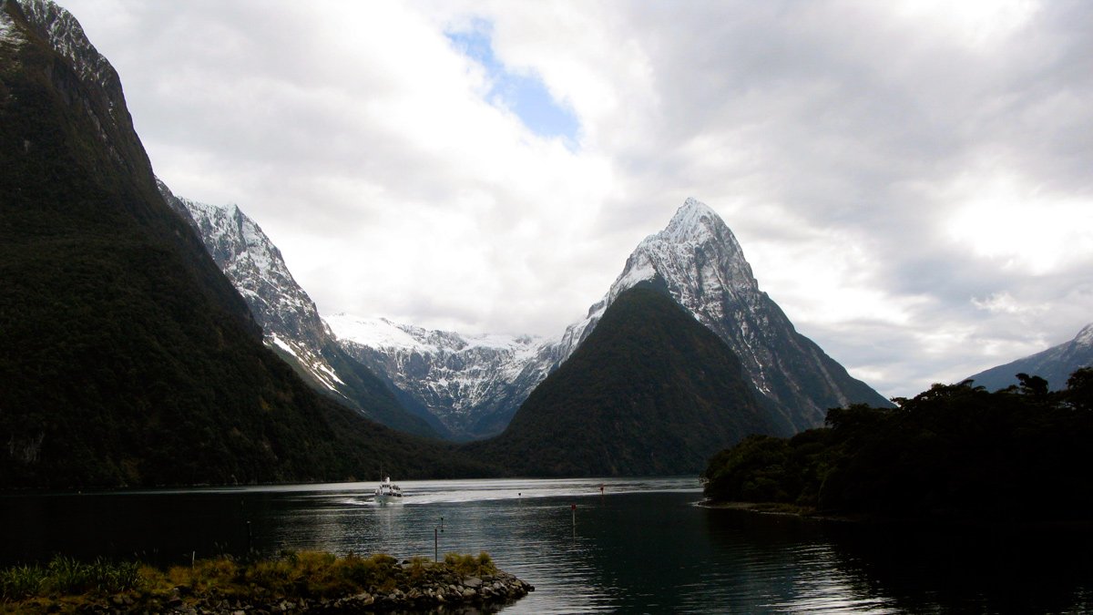 a body of water with mountains in the background with Milford Sound in the background