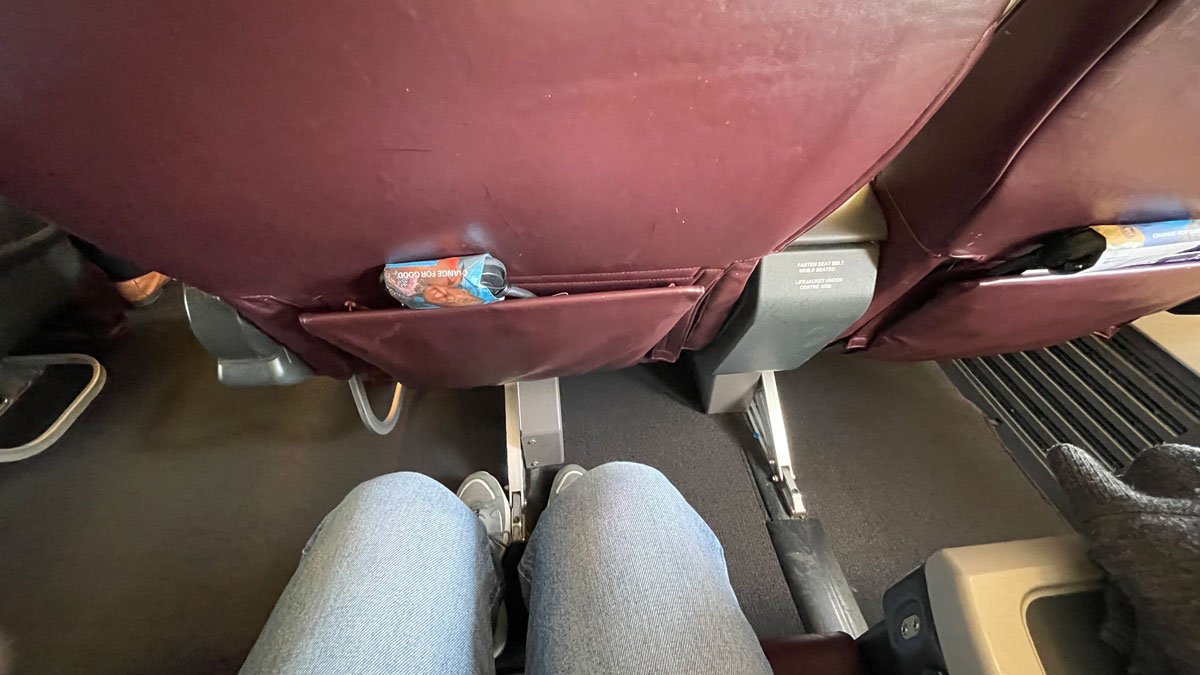 a person's legs in a seat with a bag in the pocket