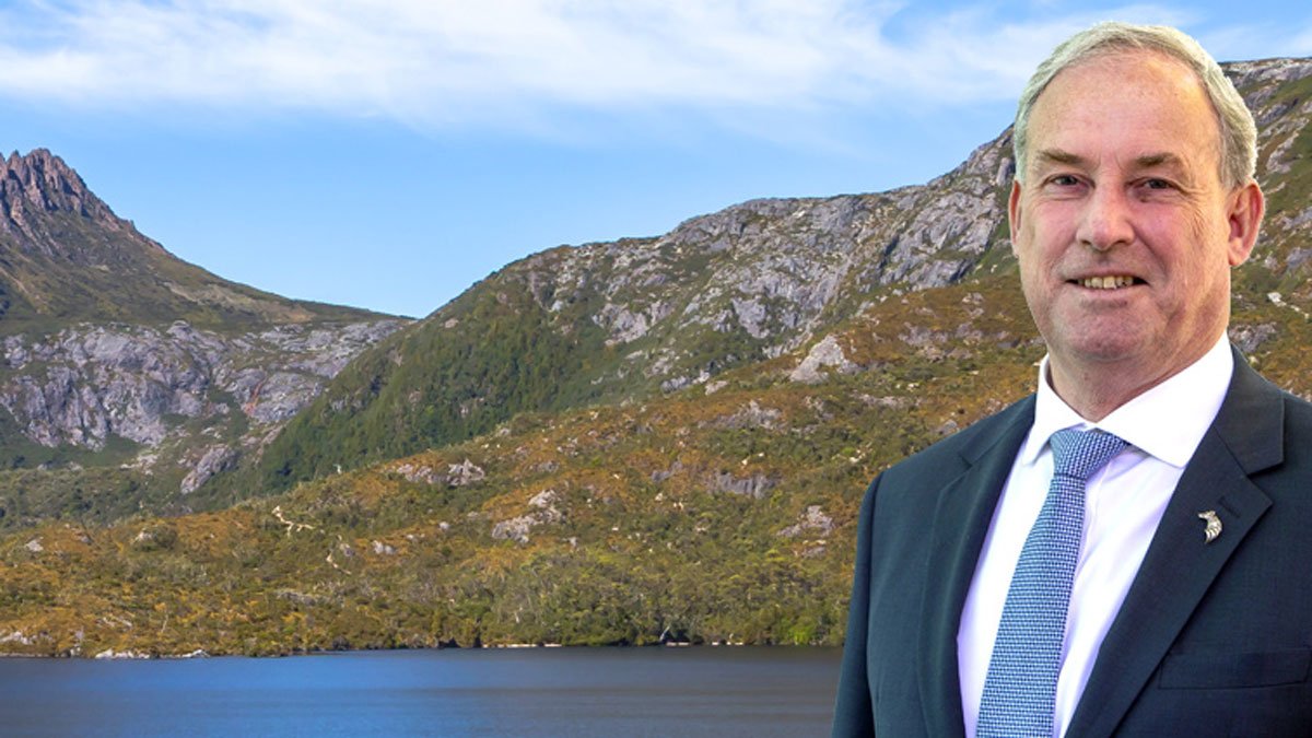 a man in a suit and tie standing in front of a body of water