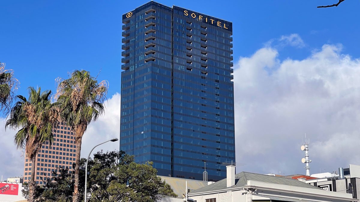 a tall building with a palm tree and blue sky