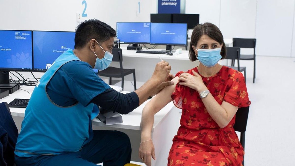 a man in a medical mask giving a shot to a woman