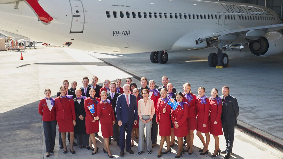 a group of people in red uniforms standing in front of an airplane