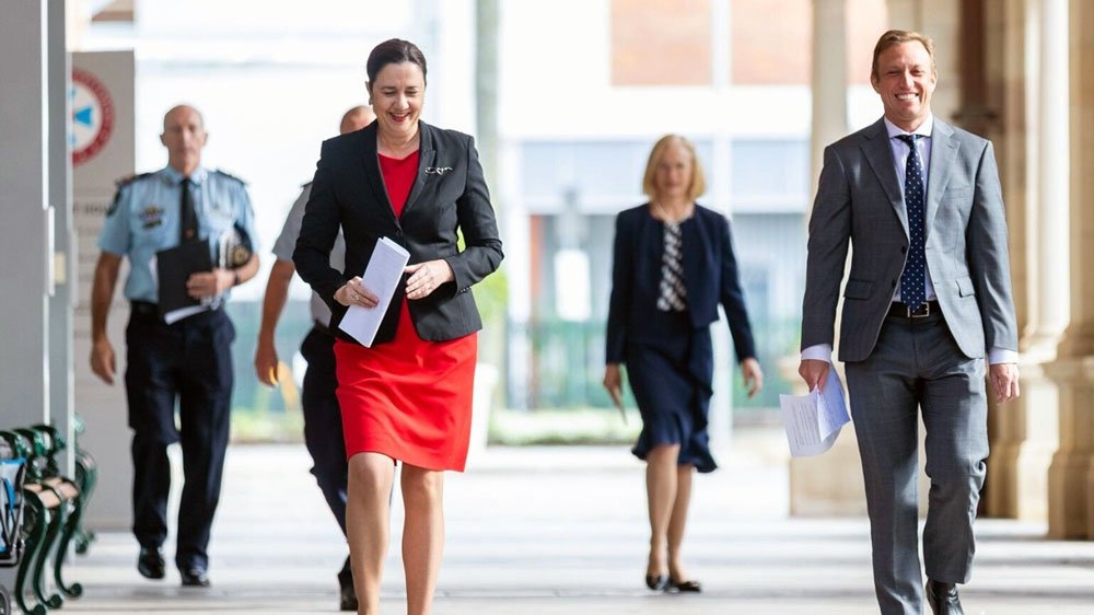 a woman in a red dress walking with a group of people