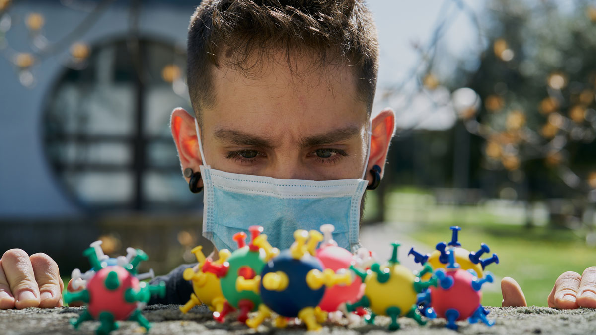 a man wearing a face mask looking at colorful spheres