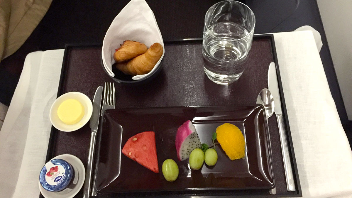 a plate of fruit and croissants on a tray