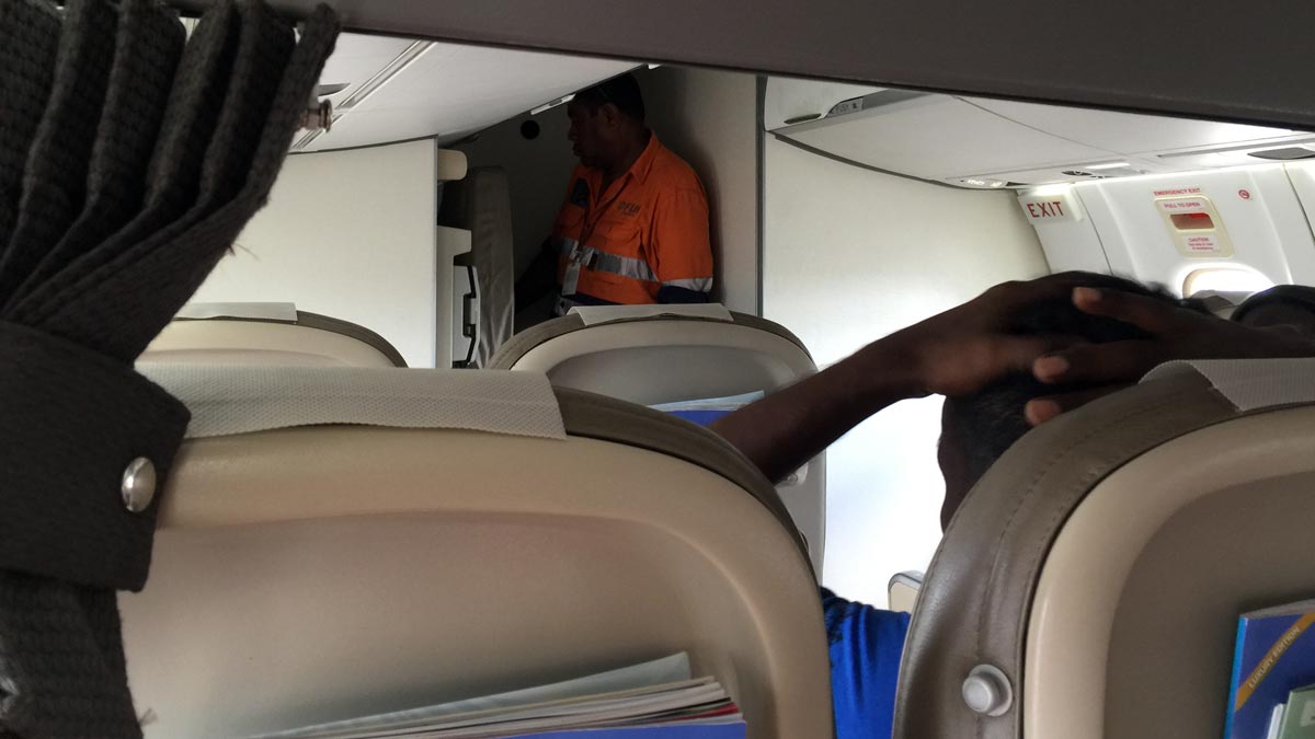 a man in an orange shirt standing in an airplane