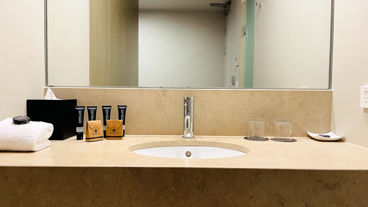 a bathroom sink with a mirror and a few bottles of shampoo