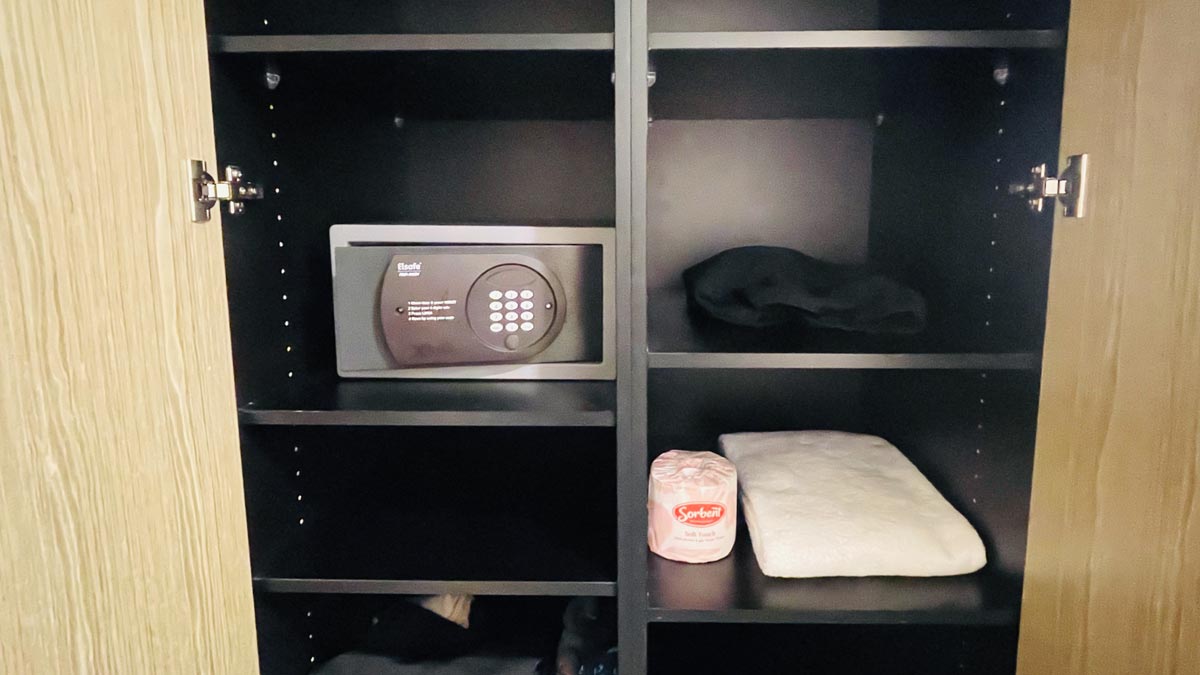 a black shelf with a safe and a roll of toilet paper