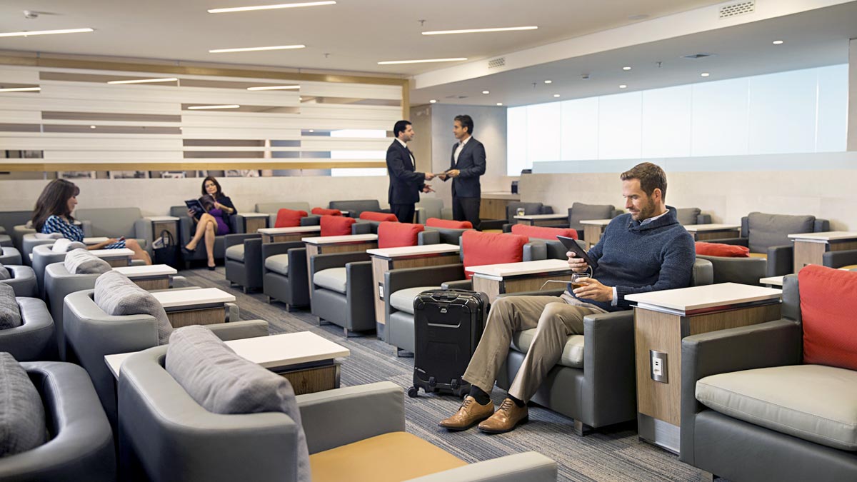 a man sitting in a lounge area with a suitcase and a woman