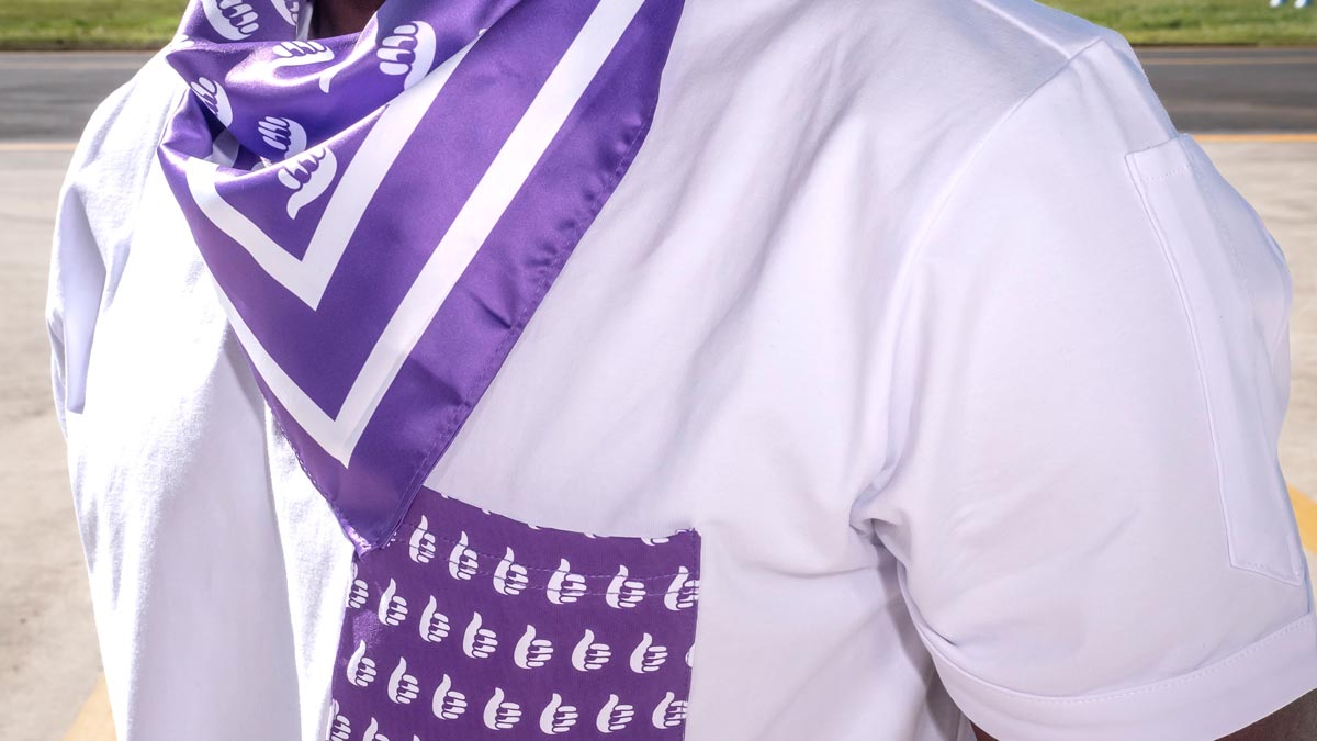 a person wearing a white shirt with a purple scarf around their neck